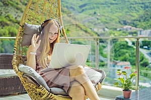 Caucasian woman sitting on the terrace working from home using computer laptop. Young woman teaches a foreign language