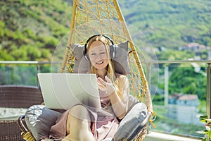 Caucasian woman sitting on the terrace working from home using computer laptop. Young woman teaches a foreign language