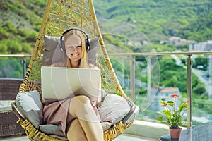 Caucasian woman sitting on the terrace working from home using computer laptop. Young woman teaches a foreign language