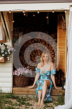 Caucasian woman sitting by woodshed.