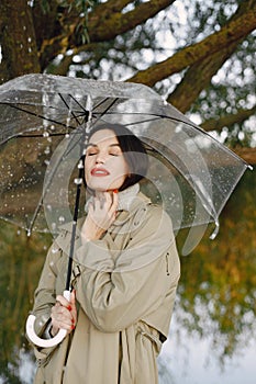 Portrait of a young woman in a coat under a transparent umbrella