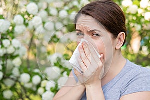 Caucasian woman suffers from allergies and sneezes while walking in the park. photo