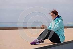 Caucasian woman in a sweatshirt measures her pulse after jogging.