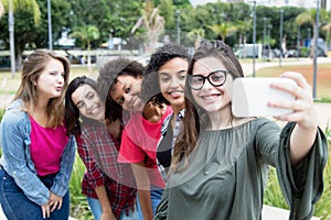 Caucasian woman taking selfie with group of international girlfriends