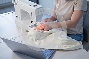 Caucasian woman teaches how to sew on a sewing machine from video. Distance education