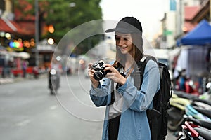 Caucasian woman tourist photographer with camera standing in busy city street in Chiang Mai Northern Thailand