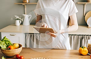 Caucasian woman use tablet computer in the modern kitchen, preparing salad