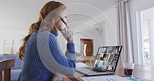 Caucasian woman using laptop and phone headset on video call with colleagues