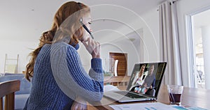 Caucasian woman using laptop and phone headset on video call with colleagues