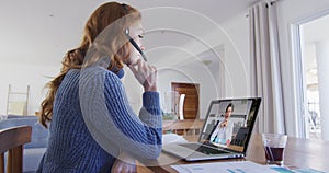 Caucasian woman using laptop and phone headset on video call with male colleague