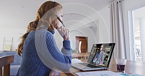 Caucasian woman using laptop and phone headset on video call with male colleague