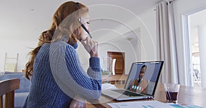Caucasian woman using laptop and phone headset on video call with male colleague