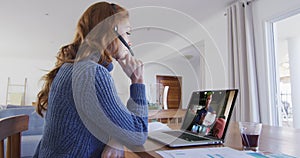 Caucasian woman using laptop and phone headset on video call with male colleague