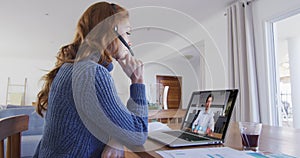 Caucasian woman using laptop and phone headset on video call with male colleague