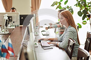 Caucasian woman using personal computer to browse the net in office library.