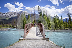 Caucasian woman walking across a foorbridge over a lake