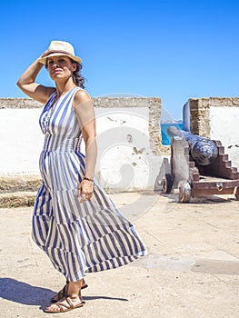 A Caucasian woman walking along an antique Latinamerican marina promenade