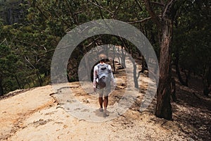 Caucasian woman walking with backpack down the mountain. Traveler going camping.