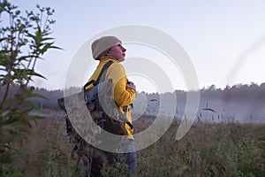 Caucasian woman walking in field alone. Girl in sport clothes hiking with backpack.