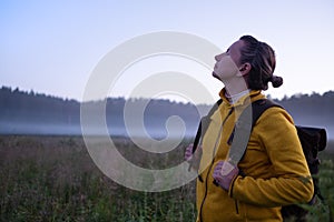 Caucasian woman walking in field alone. Girl in sport clothes hiking with backpack.