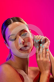 Caucasian woman wearing red lipstick and blue nail polish on pink background