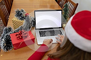 Caucasian woman wearing santa hat having video call on laptop with copy space at christmas time