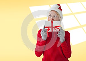 Caucasian woman wearing santa hat holding christmas gift against copy space on yellow background