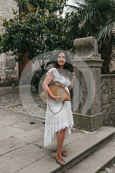 Caucasian woman wearing white drees standing in street of old town