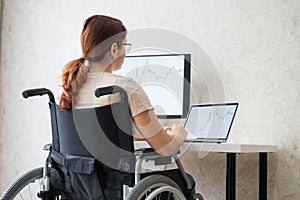 Caucasian woman in a wheelchair typing with a laptop from home. Remote work for people with disabilities.