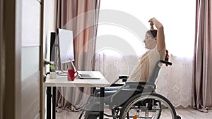 Caucasian woman in a wheelchair typing with a laptop from home. Remote work for people with disabilities.