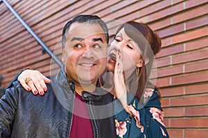 Caucasian Woman Whispering Secret in Hispanic Man`s Ear