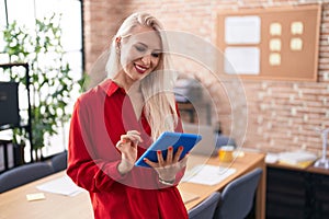Caucasian woman working at the office with tablet with a happy and cool smile on face
