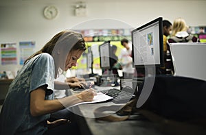 Caucasian woman writing at computer room