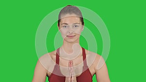 Caucasian woman yoga meditating sitting lotus, hands coupled on a green screen, chroma key.