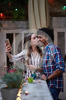 Caucasian woman and afro-american man taking selfie  in a outdoor bar. multiethnic, friends, couple, concept