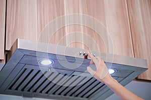 Caucasian women hand using the range hood in modern kitchen