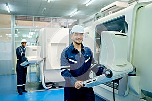 Caucasian worker and African American technician shake hand with smiling face in front of factory robotic machine during work in