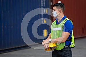 Caucasian worker in safety vest reflective holding Safety helmet with Surgical mask at work