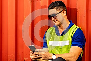 Caucasian worker sitting leaning to container box and using smart phone when his break