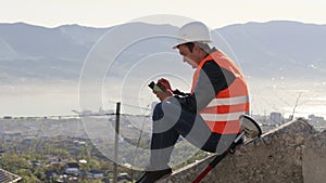 Caucasian worker in vest and helmet sitting on the concrete plates