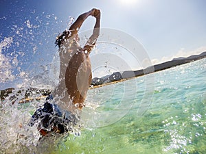 Caucasian young boy jumping in water, playing and having fun