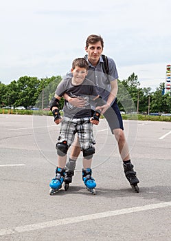 Caucasian young boy in roller-skating and father skate together on city streets