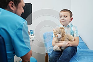 Caucasian young boy sitting with toy in doctor office