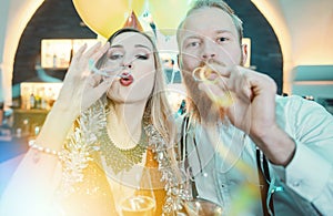 Caucasian young couple blowing the bubbles in party