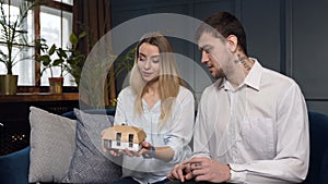 Caucasian young couple choosing model of house in the architect office.