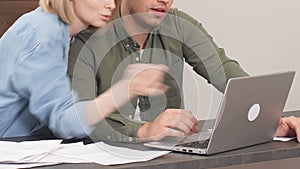 Caucasian young couple reading and analyzing bills sitting at table