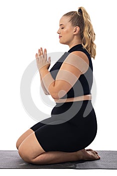 Caucasian young female plus size model on white background wearing black yoga outfit practicing