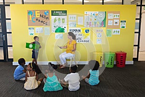 Caucasian young female teacher and african american elementary students looking at classmate