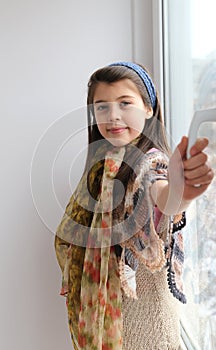 Caucasian young girl smiling, opening window