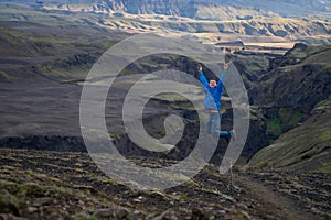 Caucasian young guy jumping in over mountain and canyon background on the way of Laugavegur trail, Iceland. Promoting